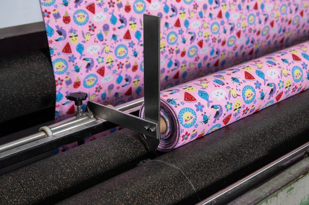 Rolo de malha estampada sendo enrolado na máquina de revisão